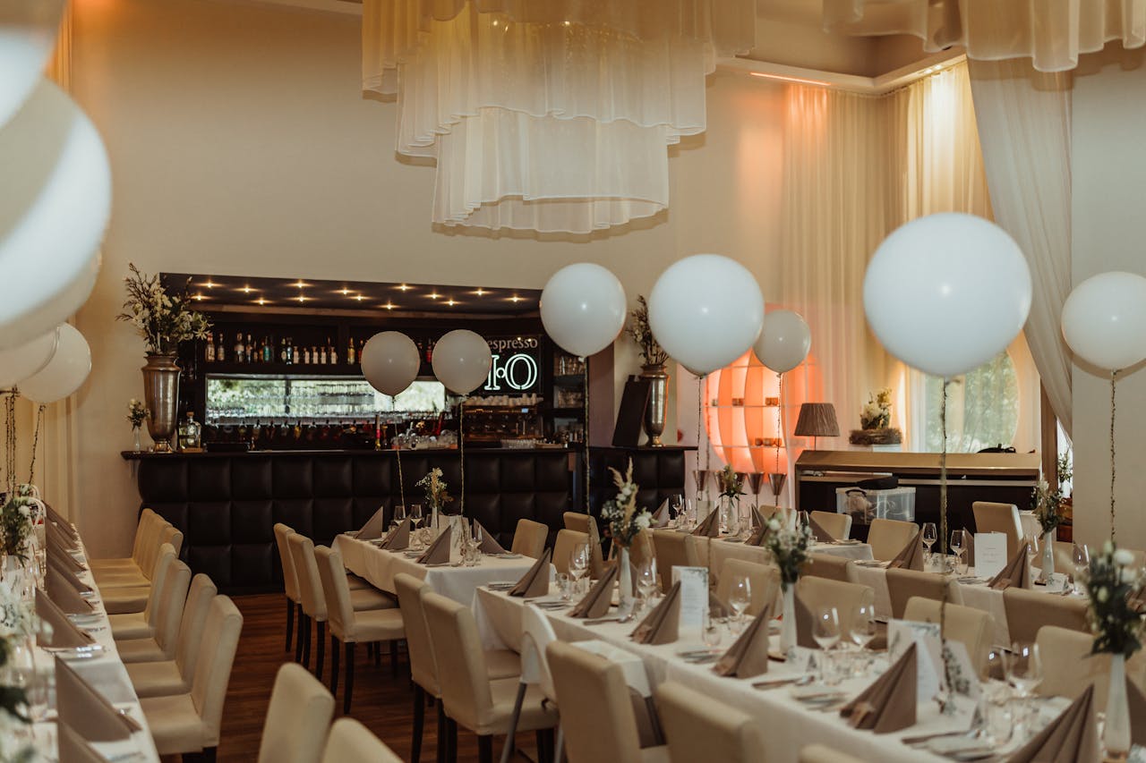 A beautifully decorated restaurant venue with white balloons, perfectly set tables, and a cozy ambiance.